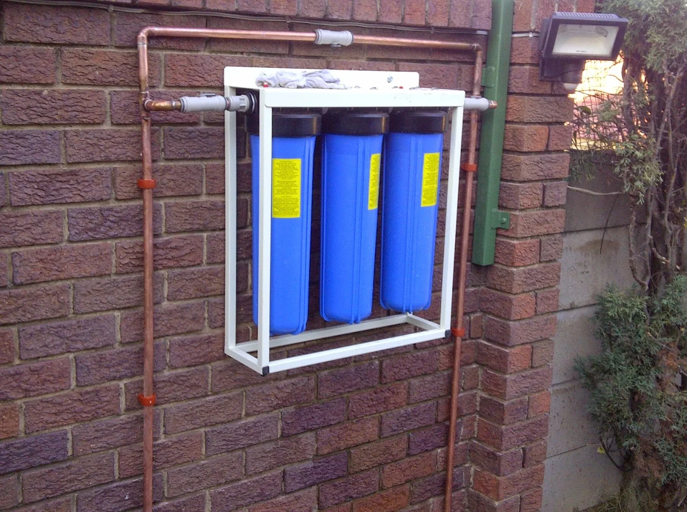 Three-stage whole-house water filtration system installed in copper pipework